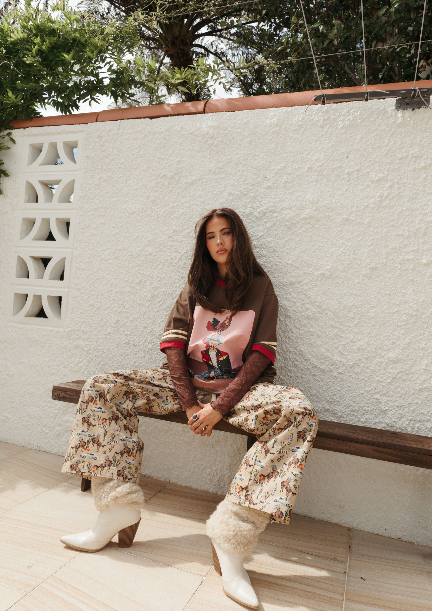 Model sitting wearing Deserted Pant showcasing western cowboy print pattern and comfortable loose fit styling