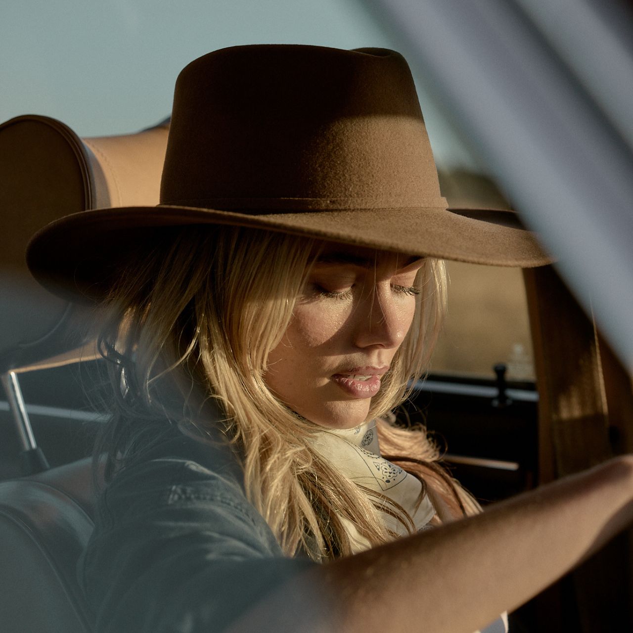 Dusty brown outback hat positioned on car dashboard showing packable travel-friendly design
