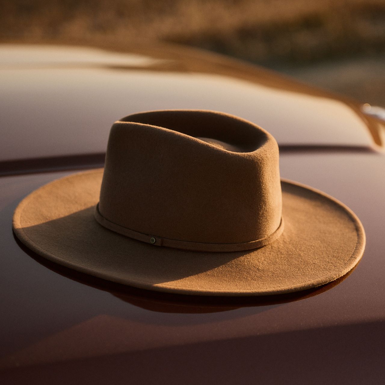 Close-up detail of dusty brown outback hat showing hat band with metal rivet accent