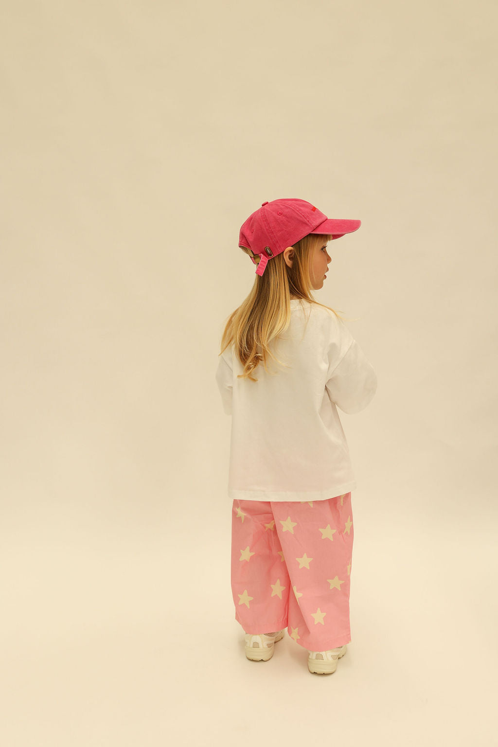 Front view of pink Dusty Star Pants with yellow star pattern and elastic waistband on child model