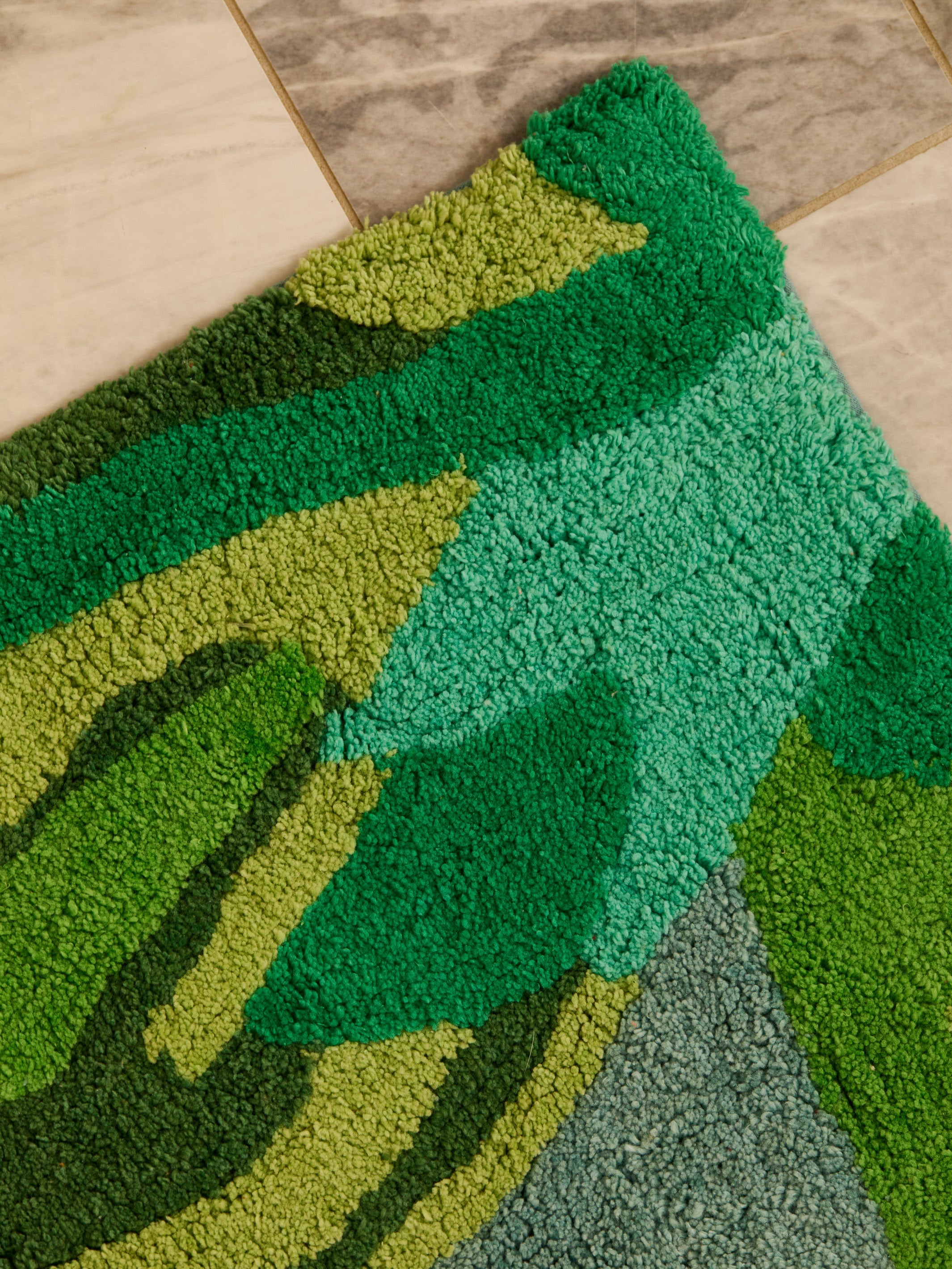 Corner detail of Dutch Floral Green Bath Mat showing hand tufted cotton pile and color variations