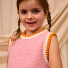 Front view of Kids Knit Vest in blush pink with orange and cream striped trim details