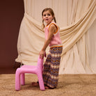 Side angle of blush pink Kids Knit Vest displaying relaxed fit and striped edge finishing
