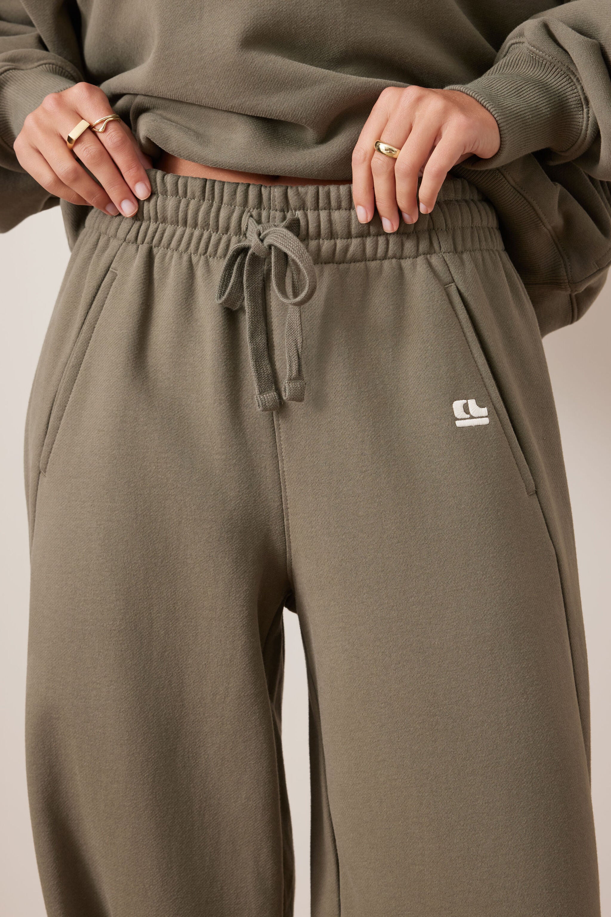 Close-up detail of elastic waistband and drawstring on washed olive barrel trackpants