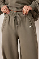 Close-up detail of elastic waistband and drawstring on washed olive barrel trackpants