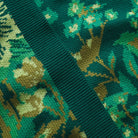 Extreme close-up of green knit fabric texture showing detailed floral jacquard pattern on Eliza pants