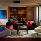Wide room view showing Eliza Cushion in mid-century modern living space with built-in shelving