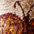Close-up detail of textured fabric showing orange burgundy and cream fibers in butterfly wing pattern