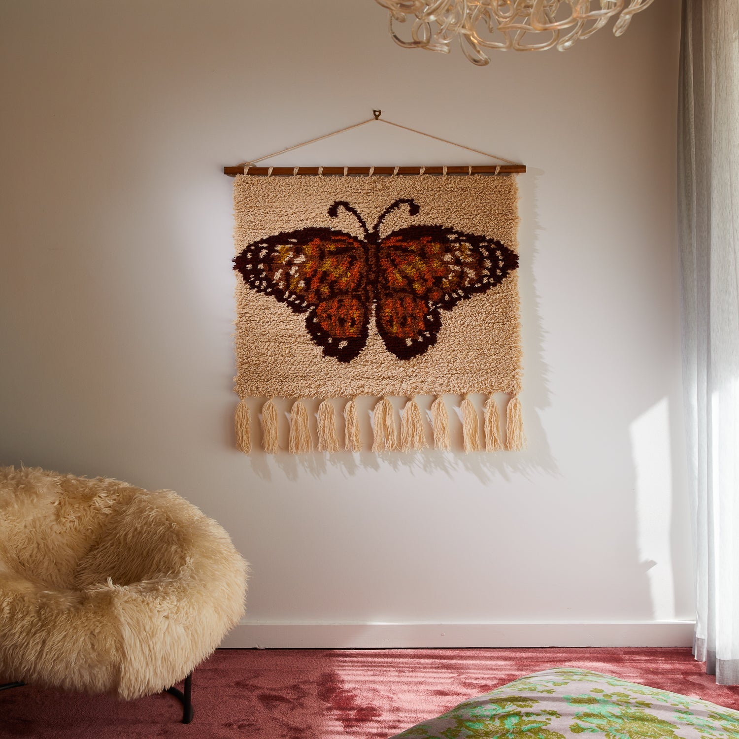 Wall mounted butterfly tapestry with cream tassels and wooden rod in bright room corner setting