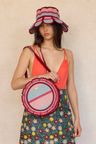 Model wearing Lorna Murray Escape Mini Love Note Tote with striped blue pink burgundy circular design and matching hat