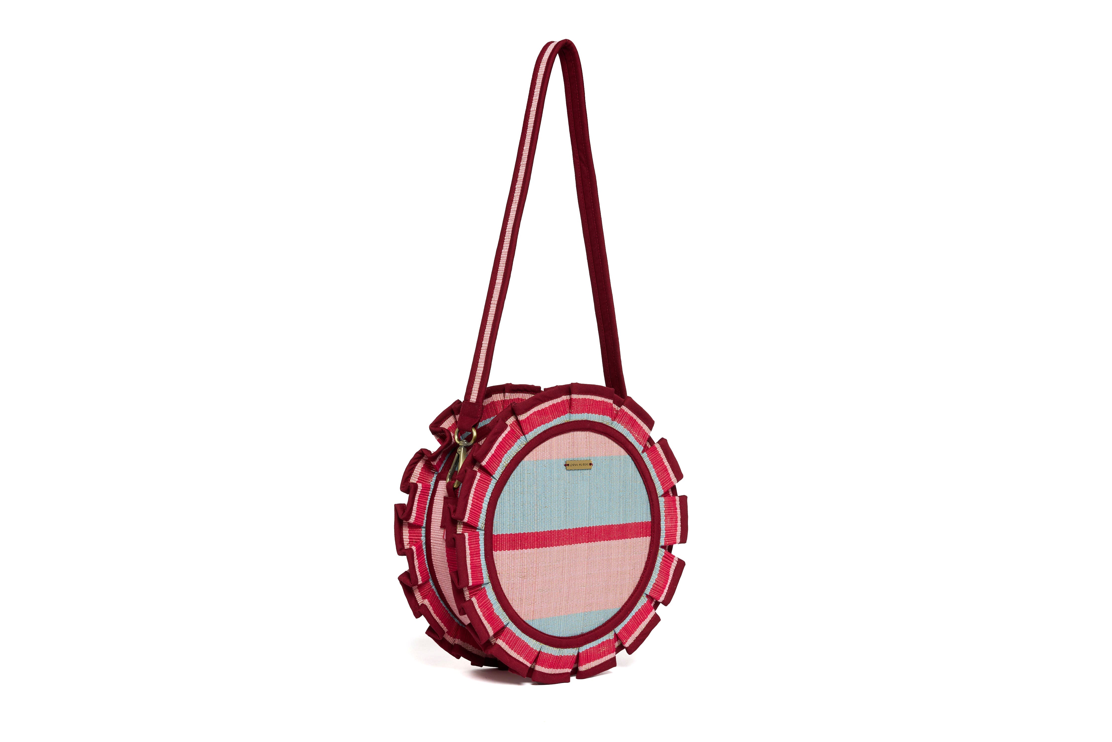 Side angle view of Escape Mini Love Note Tote showing circular shape with striped pattern and burgundy shoulder strap