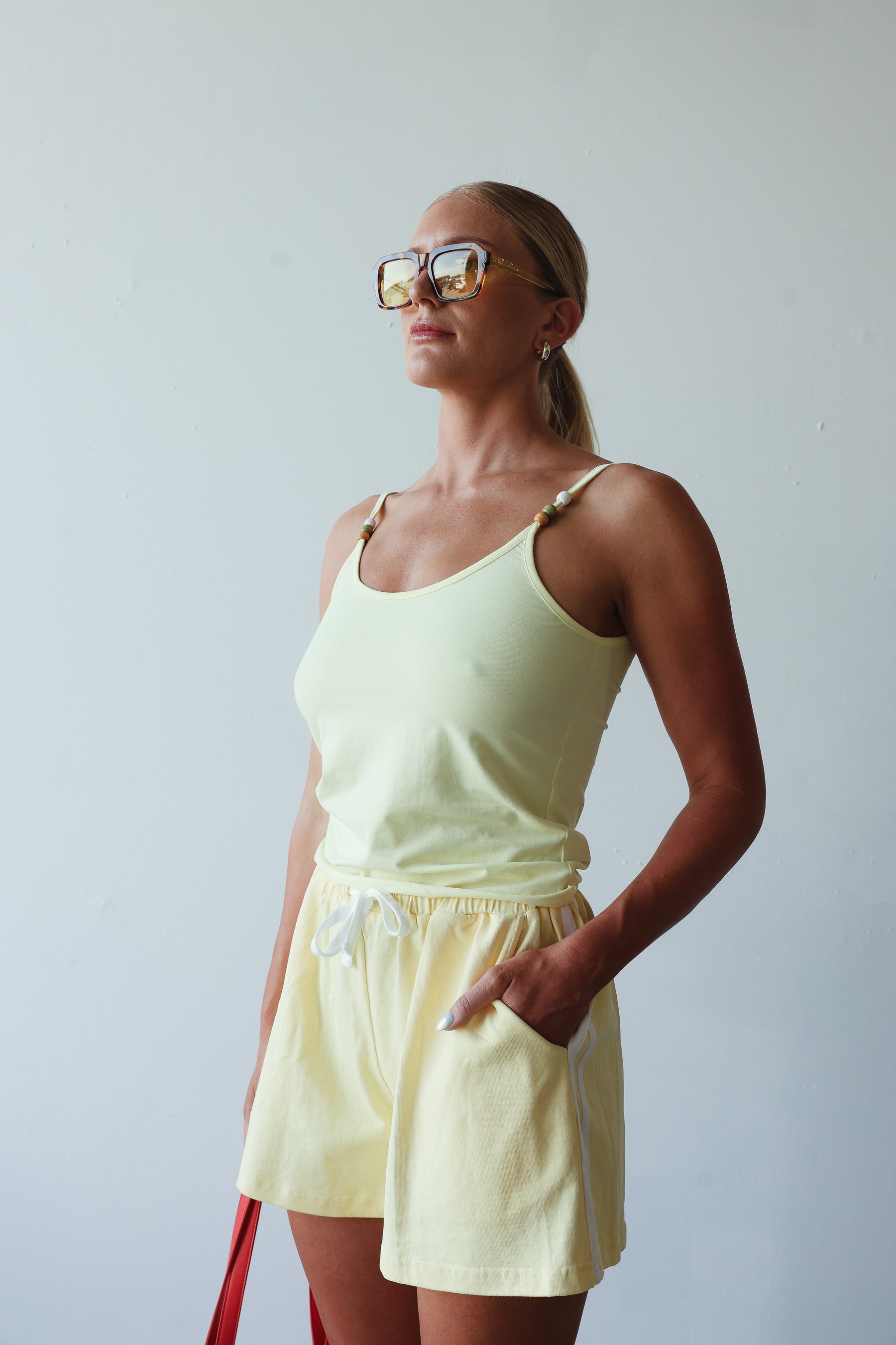 model wearing cotton yellow shorts with white stripes and yellow singlet - By Billie