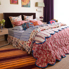 Evette Scalloped Quilted Coverlet by Sage and Clare - maroon and orange stripes on one side, red floral design on the opposing side. 