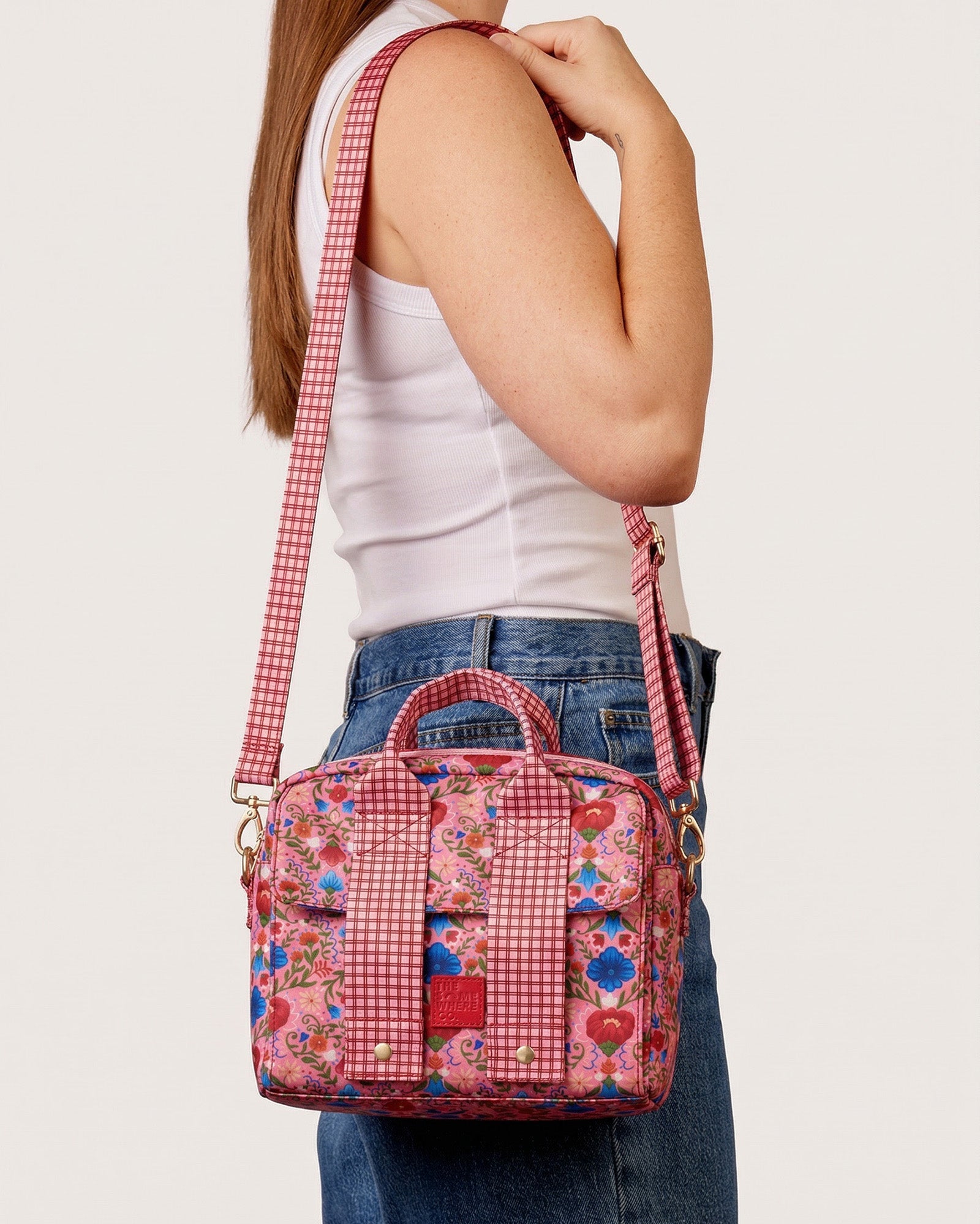 Fable lunch tote worn crossbody with pink floral print and red gingham shoulder strap