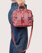 Fable lunch tote carried by hand showing floral print and gingham crossbody strap detail
