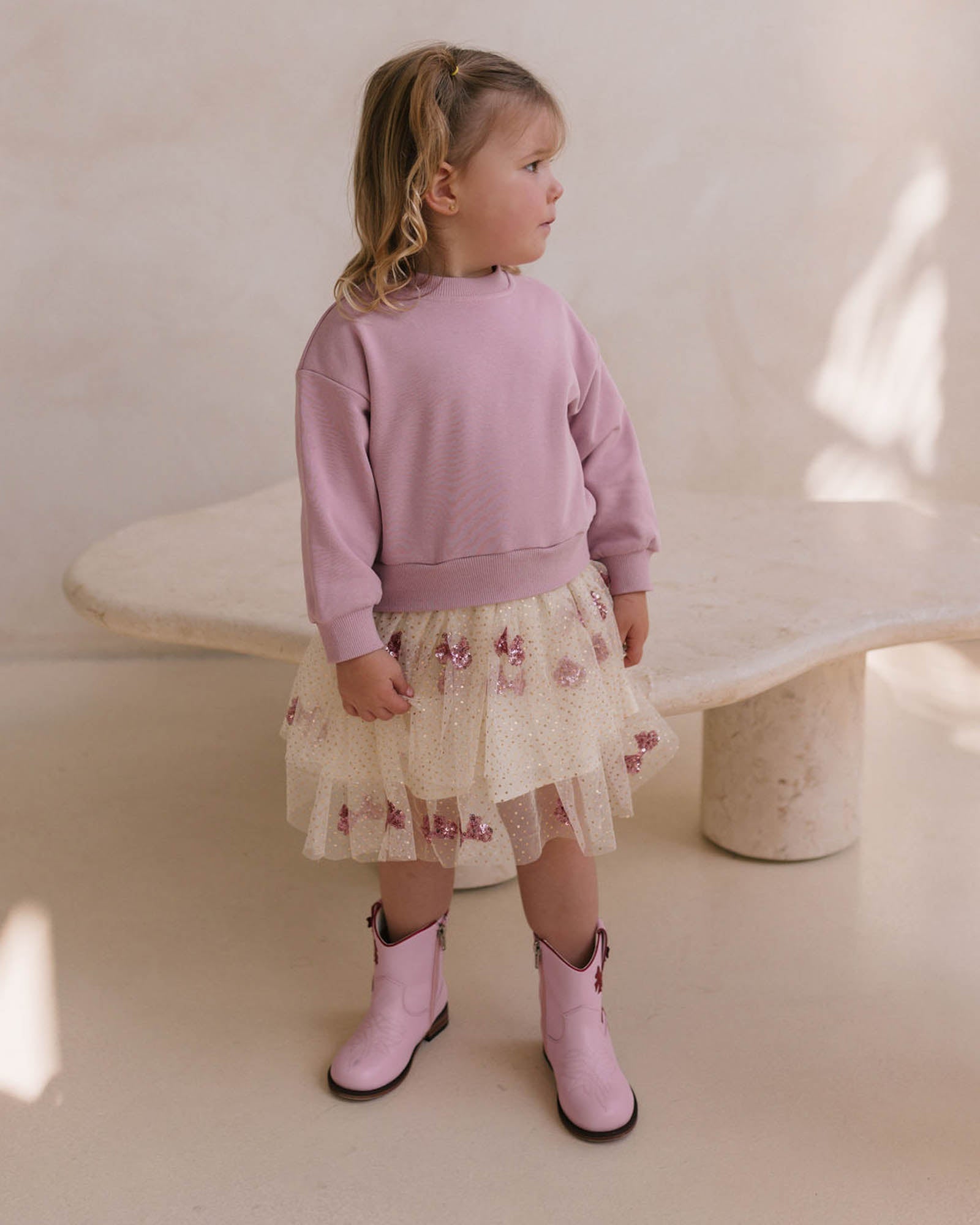 Side view of pink Faire La Fete sweater dress with ribbed sweatshirt top and floral tulle tiered skirt
