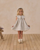Young girl wearing Florence Dress in sky stripe showing full front view with pleated skirt