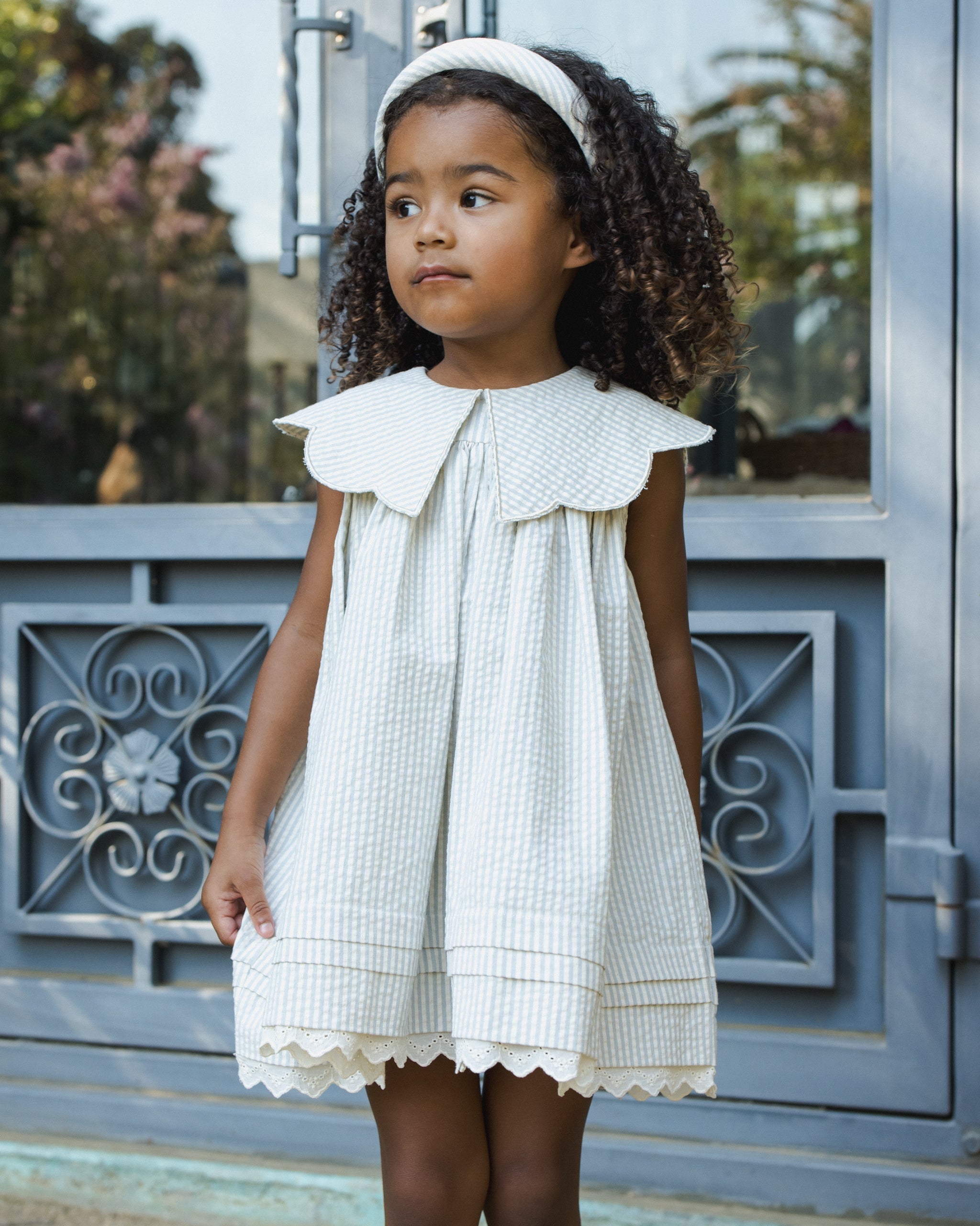Child modeling Florence Dress Sky Stripe outdoors showing eyelet hem detail