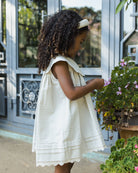 Profile view of girl in Florence Dress by Noralee with scalloped collar while picking flowers