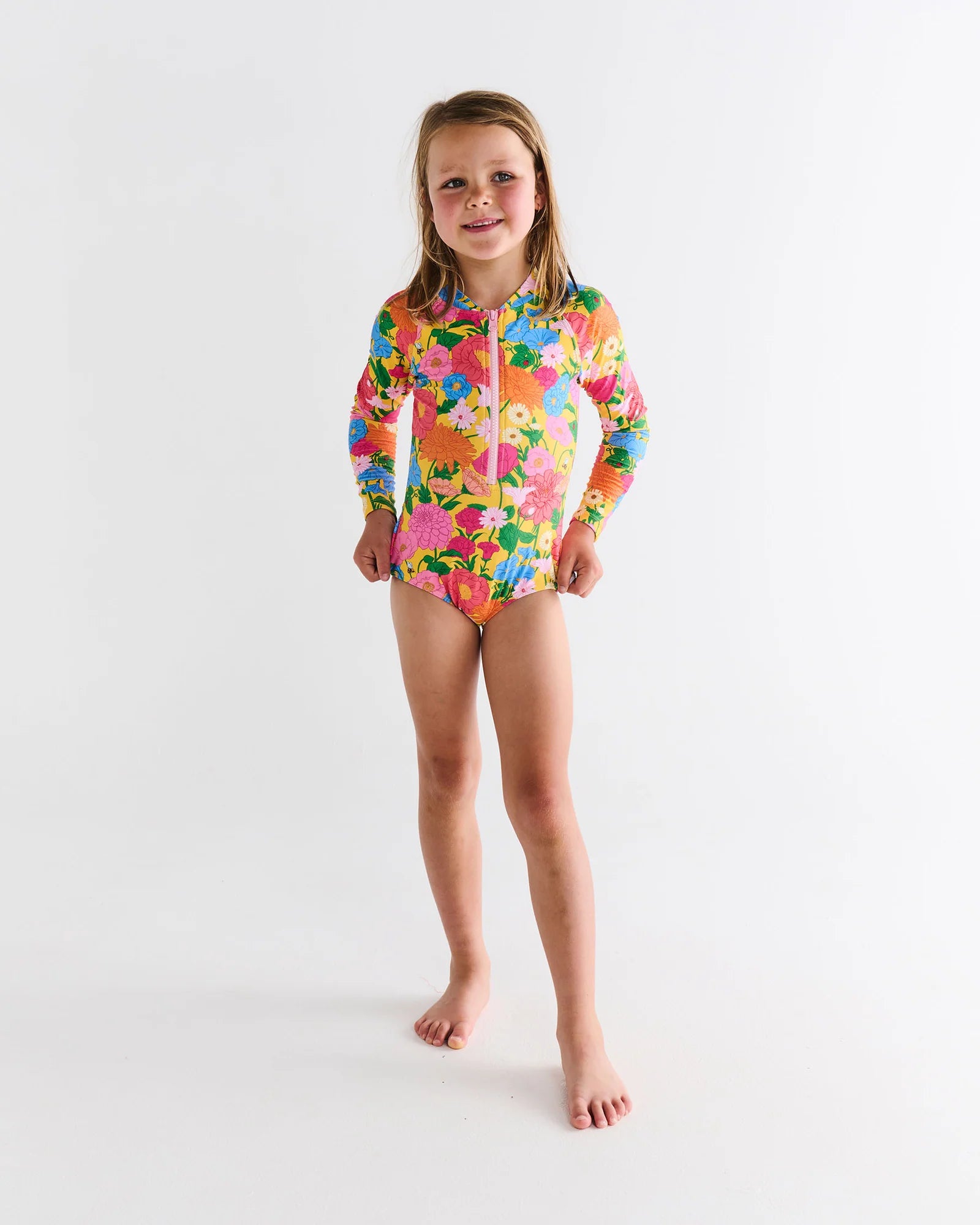 Girl wearing bright coloured floral bathers with long sleeves by Kip & Co