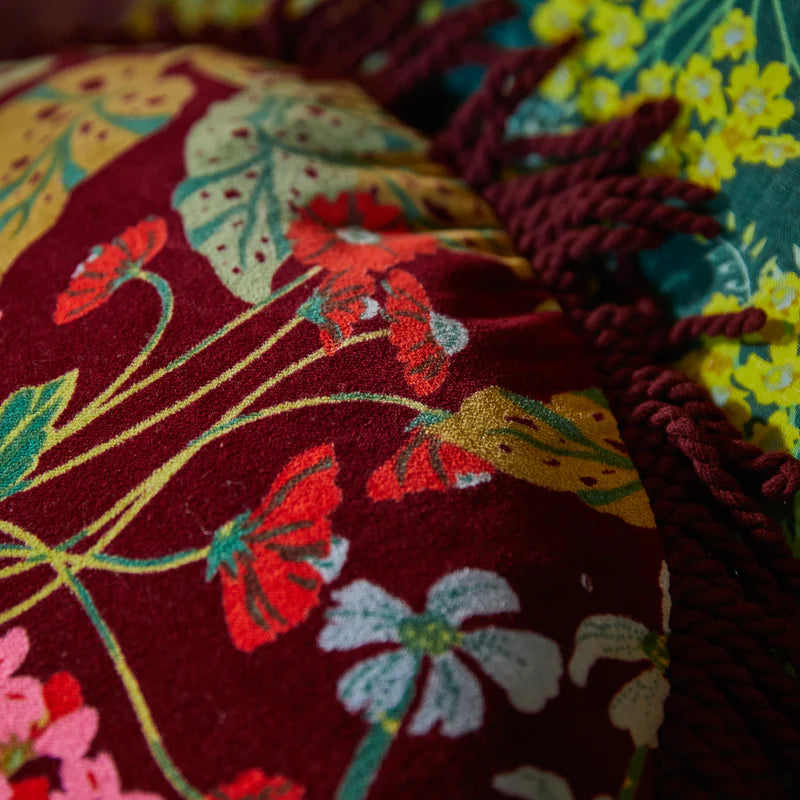 Close-up of embroidered fabric with floral patterns on a dark background - velvet floral Genevieve Fringe Cushion by Sage & Clare