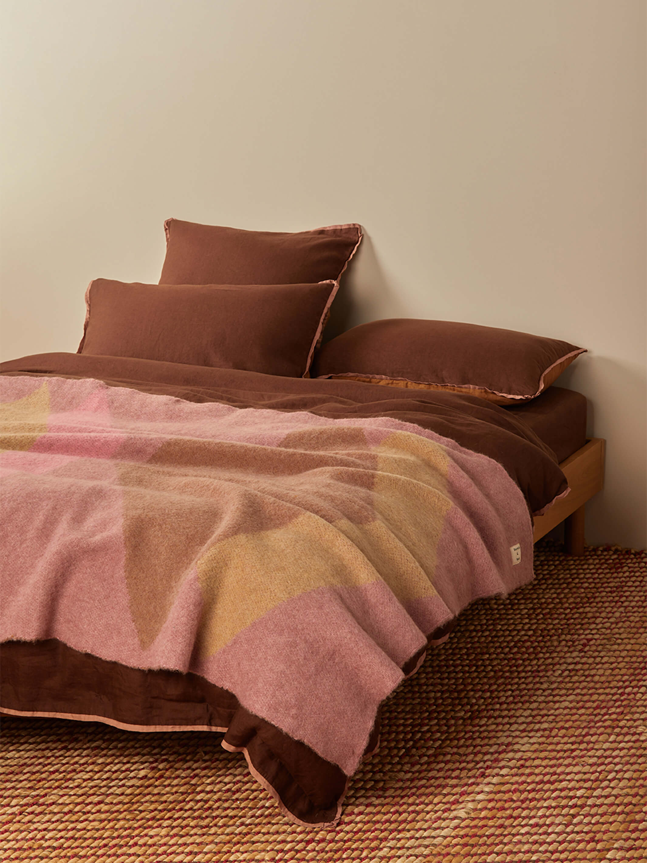 Close-up of Geometric Pink Mohair Throw showing diagonal color block pattern on bed