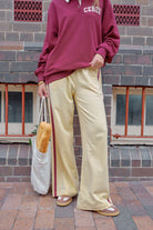 Woman sitting wearing pink wide leg track pants with white side stripe on park bench