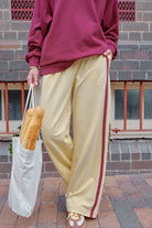 Woman walking in bright blue wide leg track pants with white side stripe crossing street
