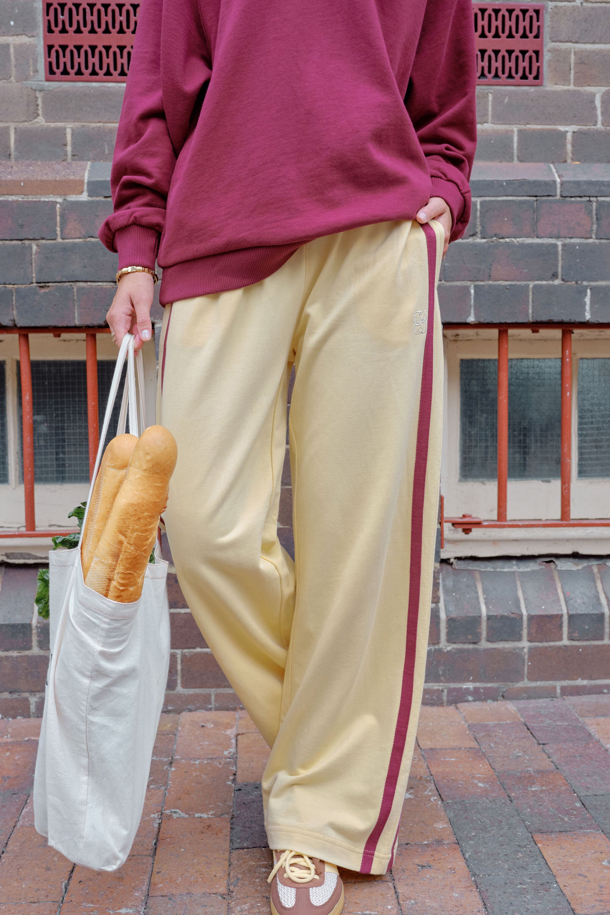 Woman walking in bright blue wide leg track pants with white side stripe crossing street