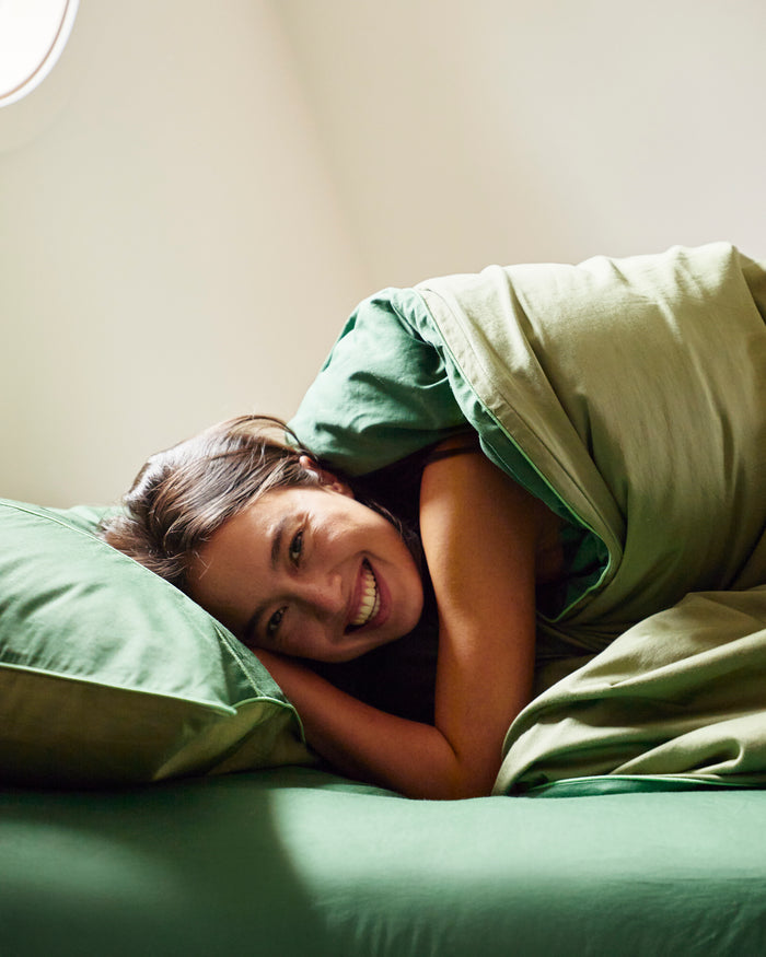 lady laying in bed with Glow In Green Bamboo Cotton Quilt Cover by Kip & Co