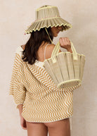 Model wearing Lorna Murray Godesis Capri Play hat in natural woven texture with pleated brim and matching tote bag