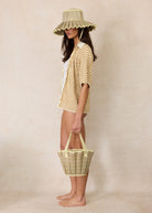 Side view of model in Lorna Murray Godesis Capri Play hat with natural woven texture and coordinating accessories
