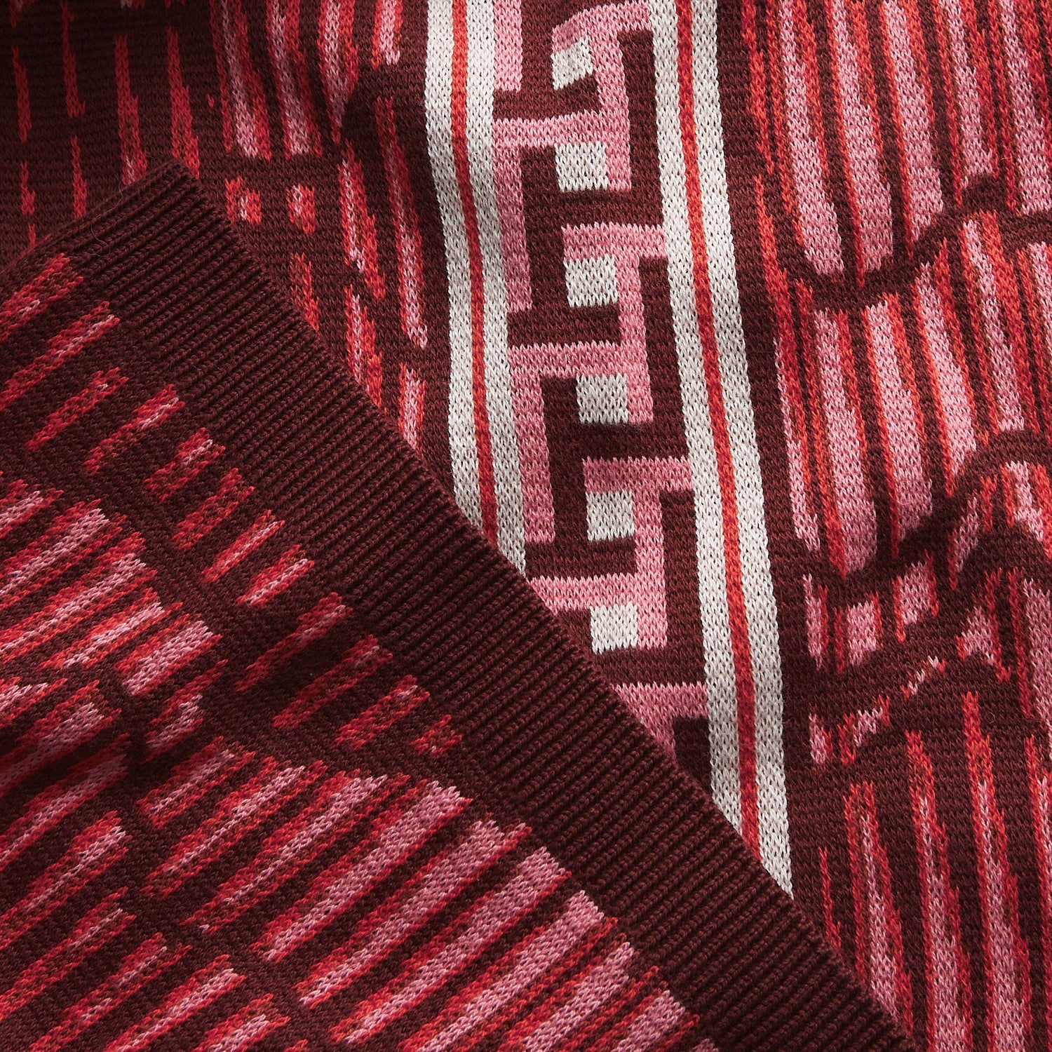 Extreme close-up of red knit fabric texture and geometric pattern on Hanna pants