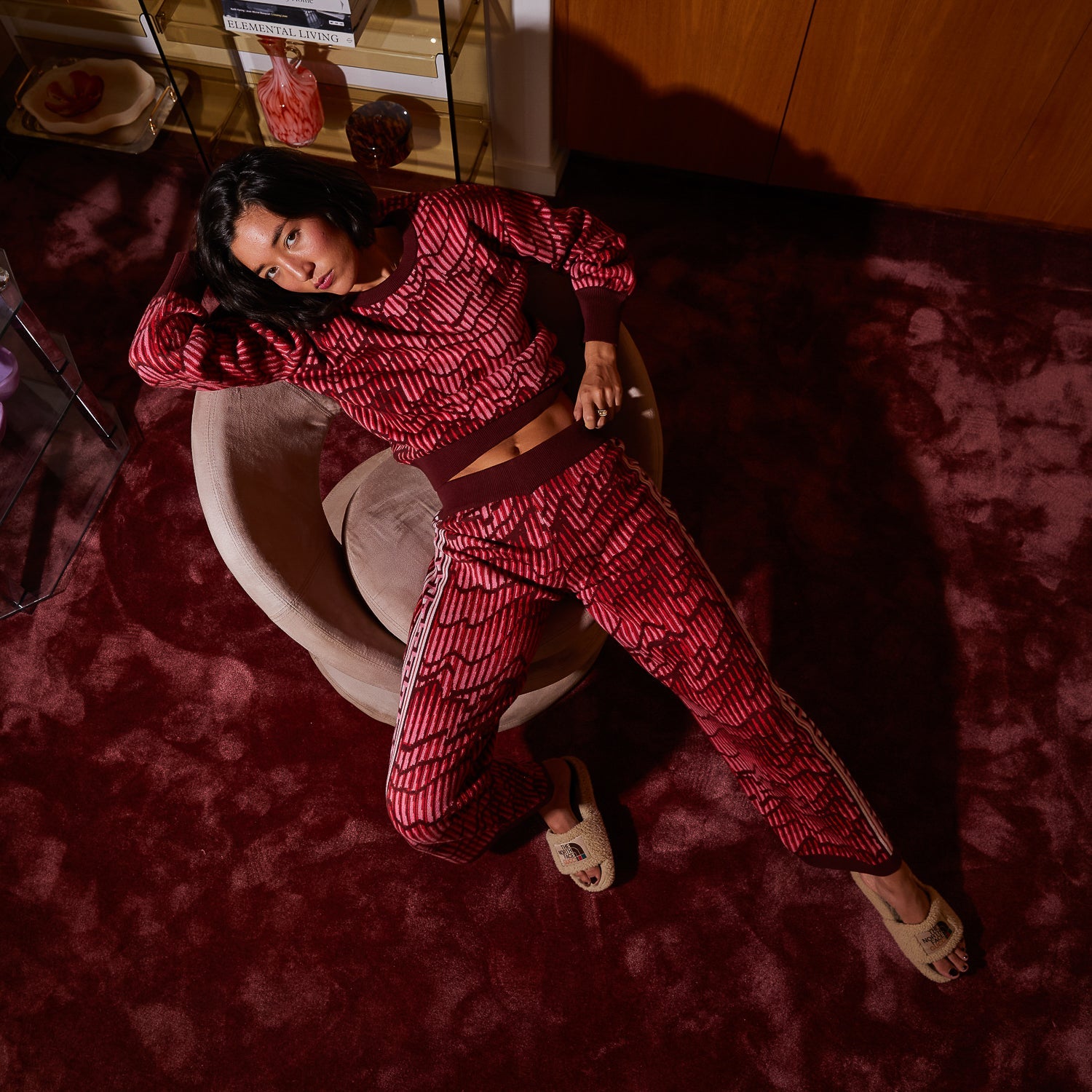 Overhead view of model wearing complete Hanna Kids Knit Pants set in red geometric pattern by Sage Clare