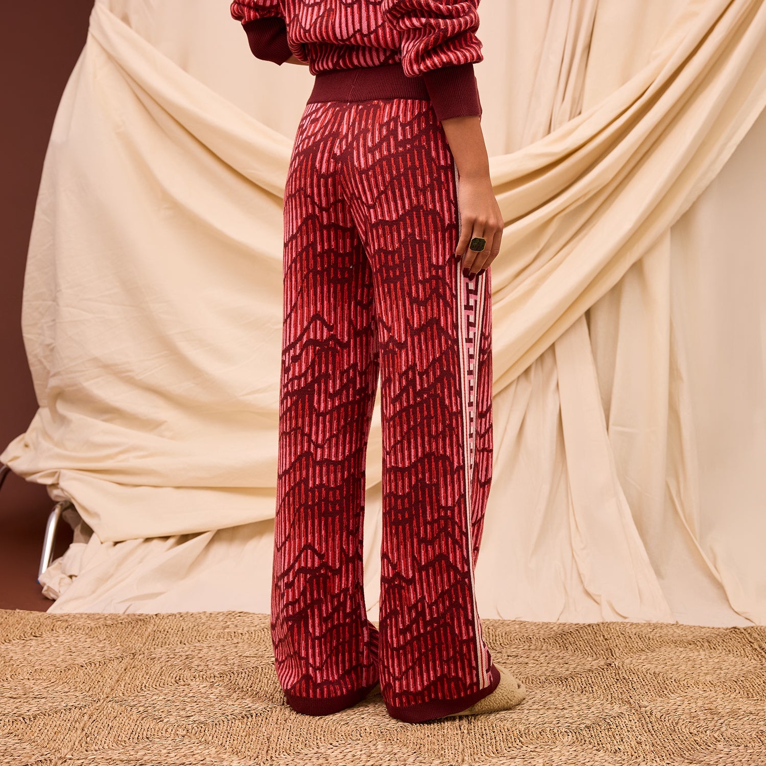 Back view of red Hanna knit pants highlighting geometric pattern and Greek key stripe down leg