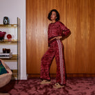 Three-quarter view of red geometric Hanna knit pants with wide leg and side stripe detail