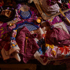 Overhead view of Hanna Pansy napkin set arranged on tablescape with colorful floral patterns and zigzag stitching