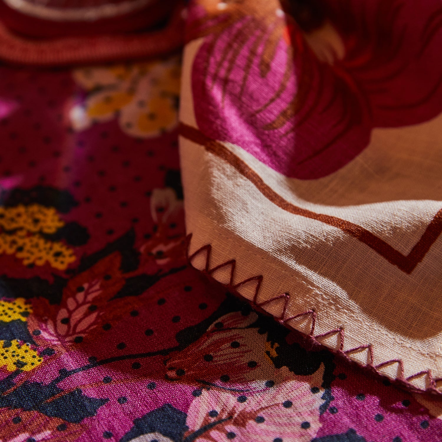 Close-up of Hanna Pansy napkins showing vibrant floral pansy print and decorative zigzag edge stitching detail