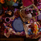 Overhead styling shot of Hanna Pansy napkins with floral pansy print arranged on dining table with decor