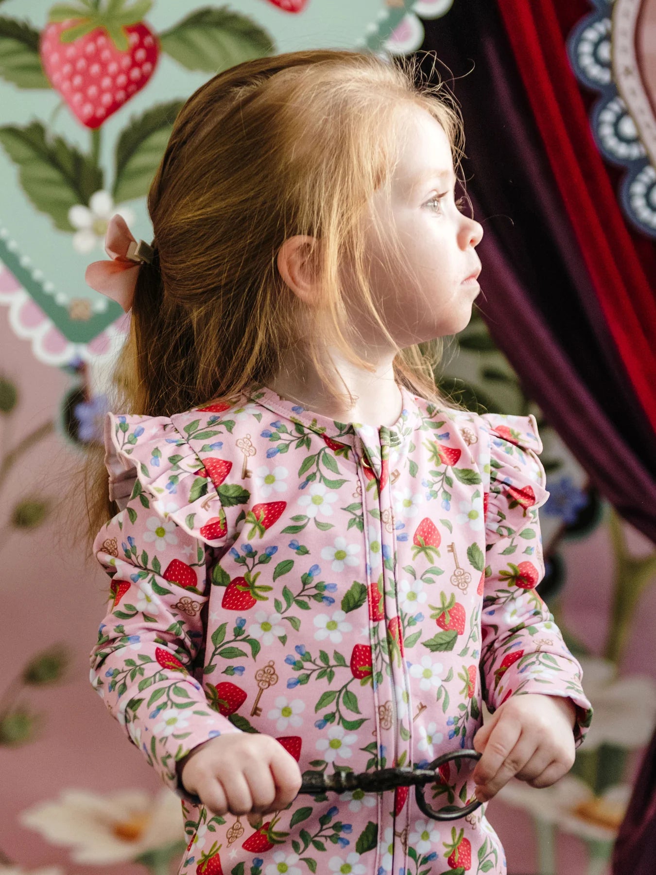 Girl wearing Pink onesie with strawberries and flowers by Fleur Harris