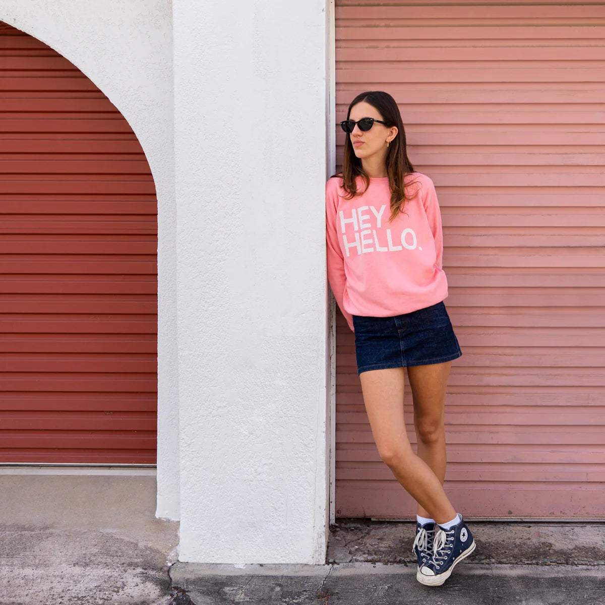 Pink sweater with white slogan text saying Hey Hello