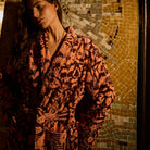 Close-up upper-body view of a rust and brown floral towelling robe with wide lapels and tied belt