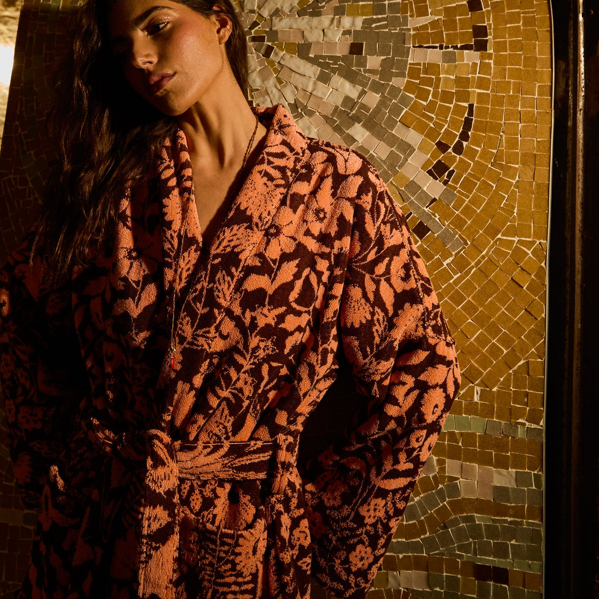 Close-up upper-body view of a rust and brown floral towelling robe with wide lapels and tied belt