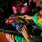 Hands opening silk pouch revealing interior zipper compartment and tropical flower pattern exterior