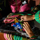 Close-up of hands accessing silk pouch showing tropical floral print and gold zipper closure