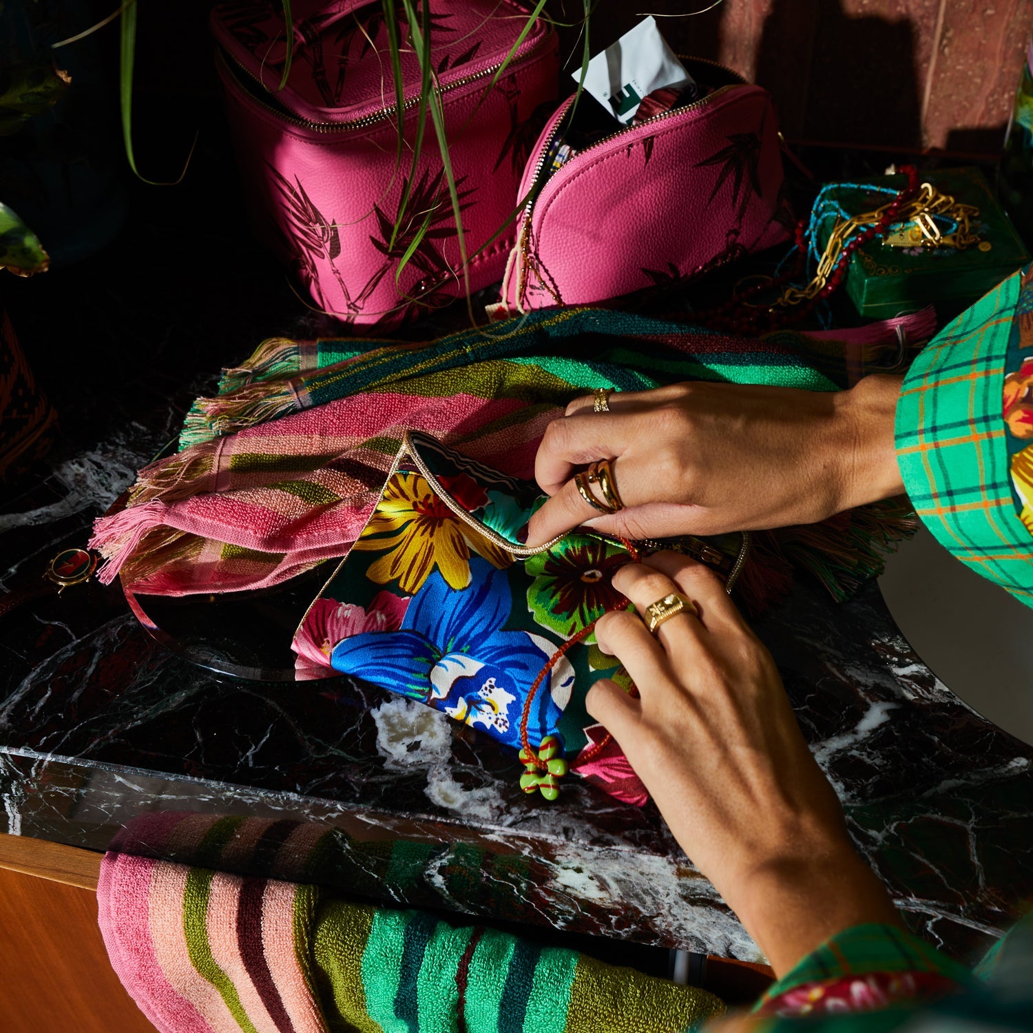 Close-up of hands accessing silk pouch showing tropical floral print and gold zipper closure