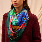 Ines Silk Scarf by Sage & Clare worn around neck showcasing vibrant tropical floral print on emerald green background