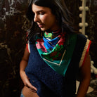 Side profile of Ines Silk Scarf styled as neck bandana showing blue and pink tropical flowers on green silk fabric