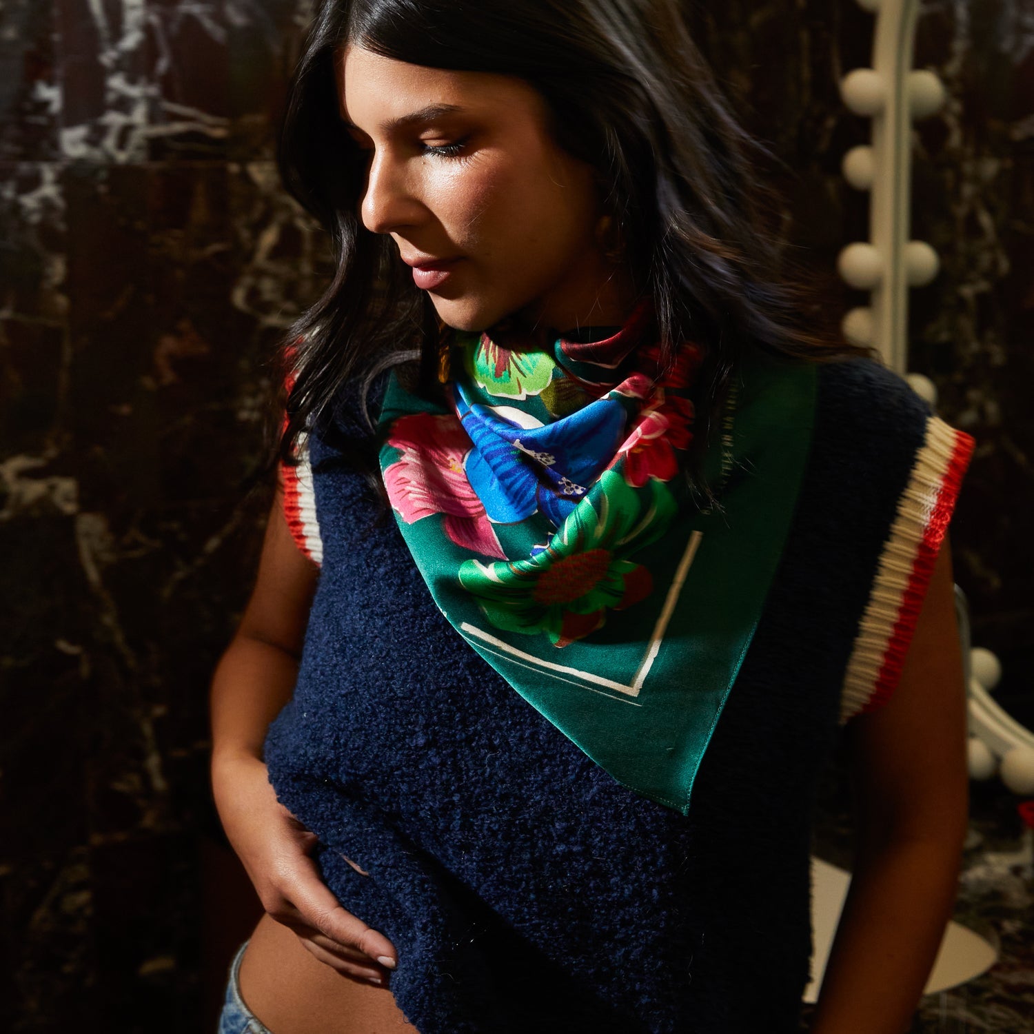 Side profile of Ines Silk Scarf styled as neck bandana showing blue and pink tropical flowers on green silk fabric