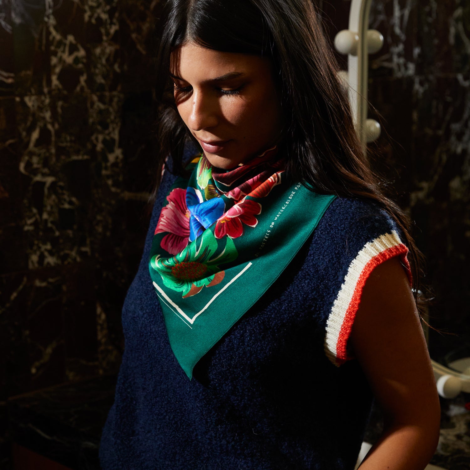 Close angle of Ines Silk Scarf worn as bandana displaying vibrant tropical blooms and emerald green border details